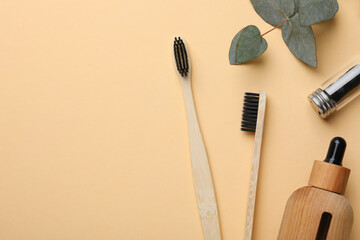 Flat lay composition with bamboo toothbrushes on pale orange background, space for text