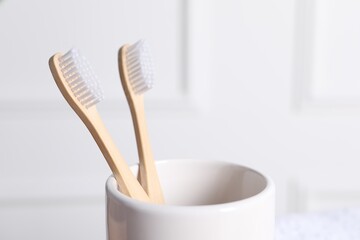 Fototapeta na wymiar Bamboo toothbrushes in holder on blurred background, closeup. Space for text
