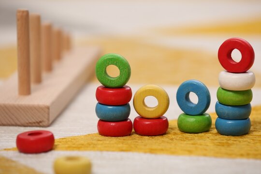 Stacking and counting game on floor indoors, closeup. Educational toy for motor skills development