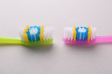 Colorful plastic toothbrushes on light background, closeup