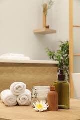 Different spa products and beautiful flower on wooden table in bathroom