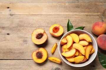 Cut juicy peaches on wooden table, flat lay. Space for text