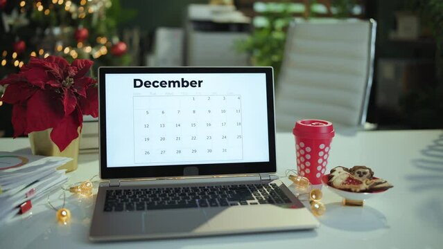 Christmas time. modern office with table, laptop, calendar, cookies and Christmas mug.