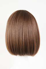 Naklejka premium Natural looking dark brunet wig on white mannequin head. Middle length brown hair on the plastic wig holder isolated on white background, back view.