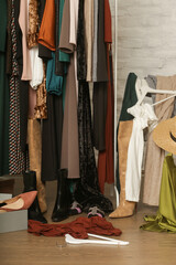 Untidy cluttered woman wardrobe with stylish clothes and accessories. Messy clothes thrown on a...