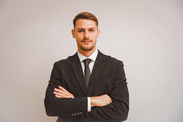 Portrait of a young businessman standing with arms crossed isolated on white background in concept Successful, committed, and happy employees