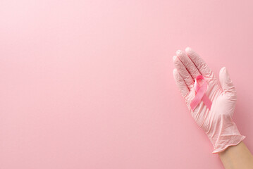 Breast cancer support theme. A first person top-view shot of girl's hand in medical glove, holding...