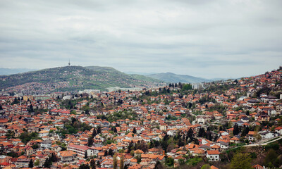 Fototapeta premium Panoramic view of the spring city of Sarajevo, Bosnia and Herzegovina. A trip to a European city in the mountains with orange roofs