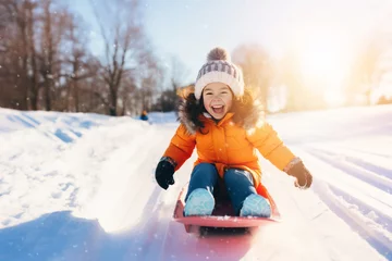 Fotobehang happy little girl sledding down the hill on sunny winter day © ronstik