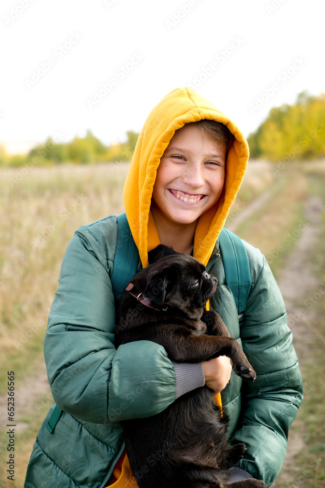 Wall mural teen boy with a dog walking in the park on a sunny yellow autumn. friendship of boy and animal, anim