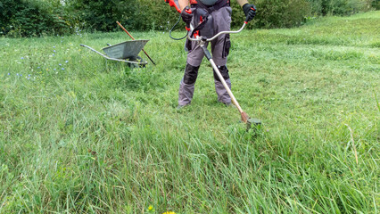 Man using brush cutter for cutting grass.