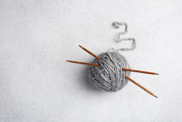 Gray clew of yarn with wooden knitting needles