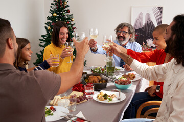 Happy family group celebrating Christmas day at home, having lunch together, toasting cheerfully....