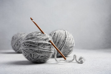 Wooden crochet hook and balls of gray yarn