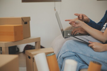 Beautiful young couple in love having fun unpacking things from cardboard boxes while moving in together in their new apartment
