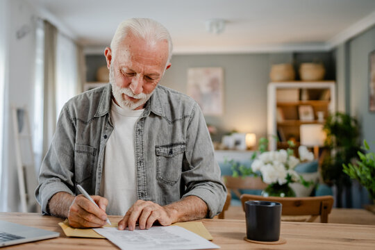 senior caucasian man open mail letter sign contract document at home