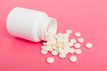 different drugs and health supplement pills poured from a medicine bottle health care and medical top view on colored background