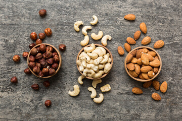 Assortment of nuts in wooden bowl on colored table. Cashew, hazelnuts, walnuts, almonds. Mix of nuts Top view with copy space