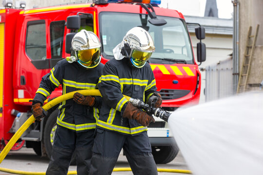 Pompiers devant un camion s'exer&ccedil;ant &agrave; lutter contre un incendie