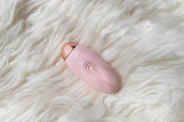 Pink vibrator - sex toy on a white fur background © vikarayu