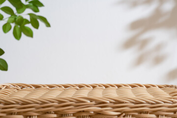 Wooden rattan podium table top blurred green leaf plant on white space nature background.Beauty...