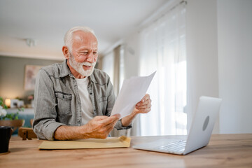 senior caucasian man open mail letter or document envelope at home