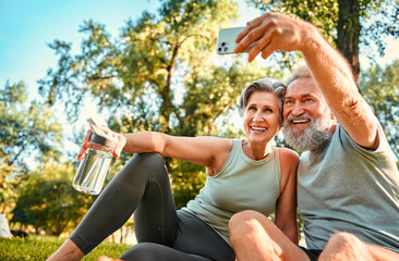 Healthy pensioners after training. Vibrant mature couple in sport outfits taking selfie on...