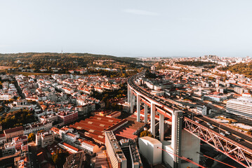 Aerial horizontal photo of streets and buildings of Lisbon on sunset. The Bridge of 25 april in...