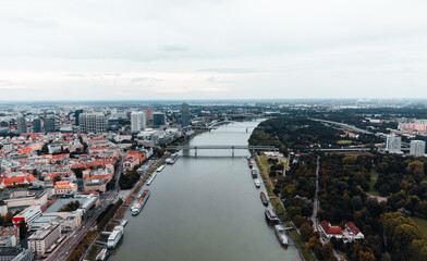 Aerial view of capital of Slovakia - Bratislava old town and Danube river with bridge on background. Panoramic view of Bratislava city on moody sunset with rooftops and danube river.