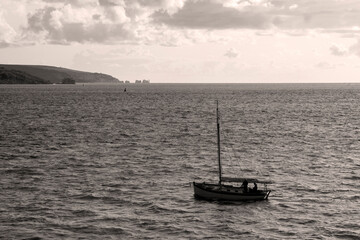 Sailing boat entering harbour and seascape in black and white