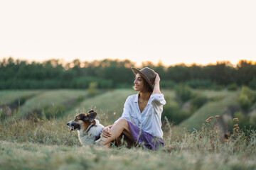 Young lady and her pet Corgi dog spending quality time in nature, overlooking scenic with grassy hills