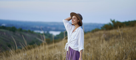 Panoramic serene hillside landscapes with elegance stylish young woman in hat spending quality time in nature at evening