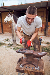 Blacksmith boy working on the anvil changing the horseshoe to a paw with tools