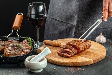 beef steaks with wine glass on a dark background. Restaurant menu, dieting, cookbook recipe top view