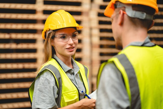 Warehouse worker logistic team wearing hard hat working in aisle between tall racks with packed goods warehouse for industry business of import, export delivery to global market, shipping management