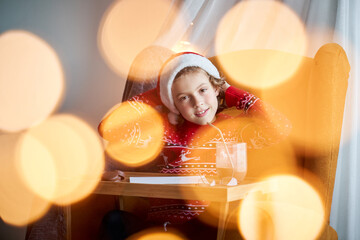 Adorable boy in Santa hat near letter