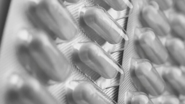 Rotating silver blister pack containing white pharmaceutical capsules in a circular motion.  the concept of virus medication, vitamins.  vertical video 