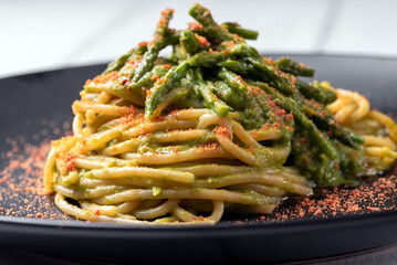 Piatto di deliziosi spaghetti conditi con salsa di asparagi selvatici e bottarga di muggine, pasta gourmet italiana, cibo europeo 
