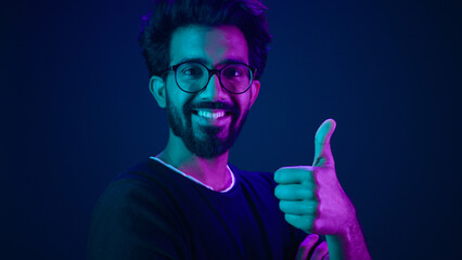Ultraviolet neon background Arabian smiling happy man hi-tech internet technology worker coding male coder computer hacker smile showing thumb up like agree recommend future modern high-tech software