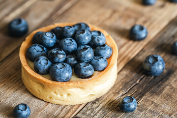 Homemade mini tart with blueberries and whipped cream on a wooden background, close up.