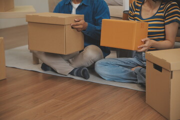 Fototapeta premium Beautiful young couple in love having fun unpacking things from cardboard boxes while moving in together in their new apartment