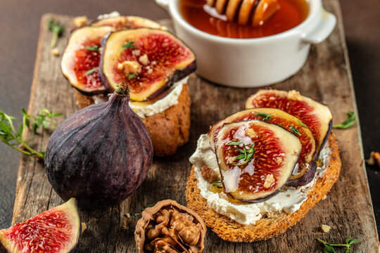 Rye bread toast with figs and ricotta cheese on a wooden board. Food recipe background. Close up