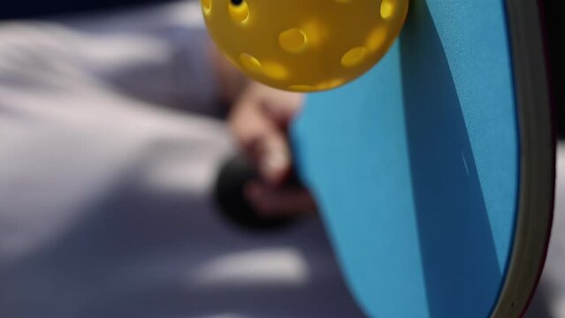 Perforated plastic ball spinning on a paddle racquet in slow motion