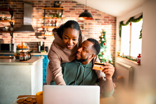 Young African American couple online shopping on a laptop during the Christmas and new year holidays at home