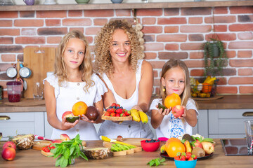 Mother and daughters cooking together in the kitchen. Healthy food concept. Portrait of happy family with fresh smoothies. Happy sisters.