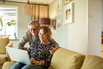 Senior Caucasian couple using the laptop on the couch at home