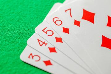 Combinations of cards in poker, straight flush five cards of red diamond suit from three to seven, selective focus