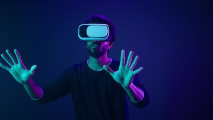 Cyber space gamer male Arabian man in VR glasses excited playing experience metaverse virtual reality cyberspace gaming play AR Indian guy with 3d goggles helmet happy meta universe neon ultraviolet