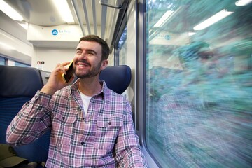 Handsome man making a call from a train
