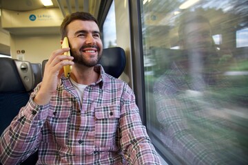 Handsome man making a call from a train 